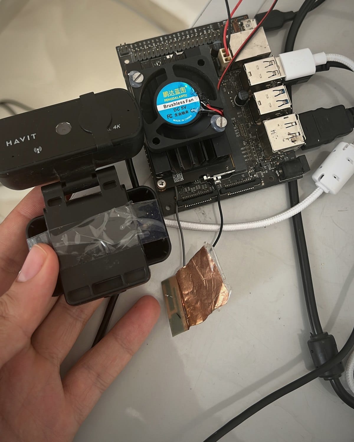 Photograph of the real EyRoad proof-of-concept on a workbench: an NVIDIA Jetson Nano with heatsink and fan, jumper wiring, and a USB camera held in hand